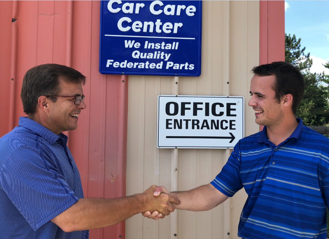About Our Agency - Happy Insurance Agents Shaking Hands in Front of the Car Care Center