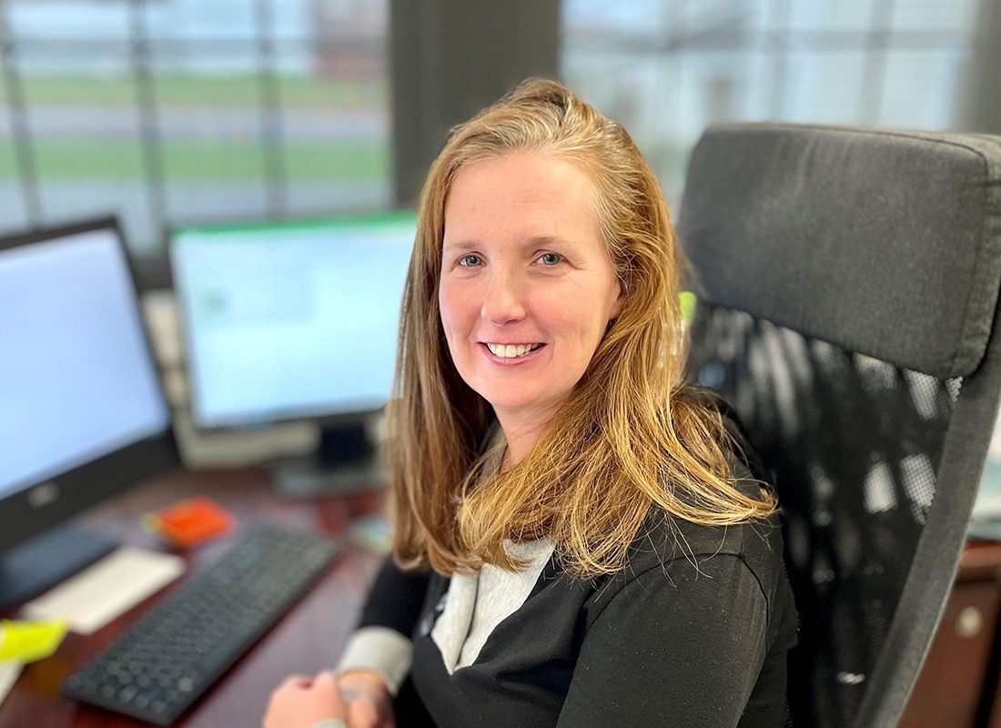 Contact - Portrait of Jen McElhaney Sitting Behind her Desk in Front of the Computer at the Covenant Insurance Office