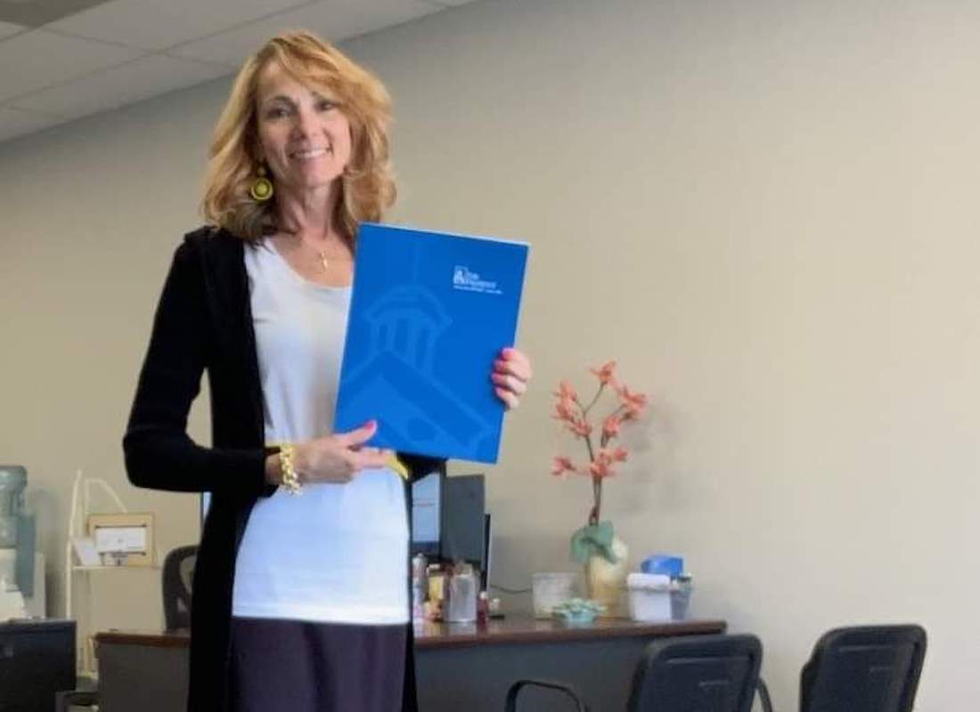 Join Our Team - Phillis posing with a blue Erie Insurance folder