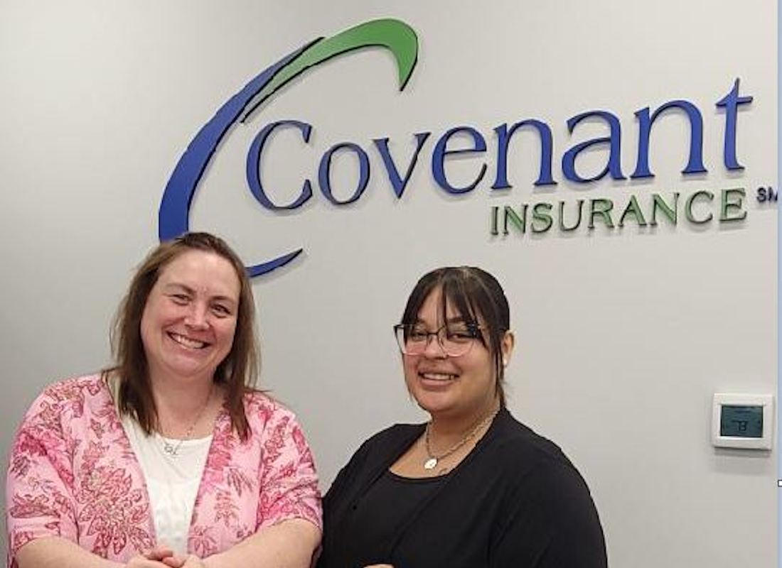 Service Center - Closeup Portrait of Two Smiling Female Employees Standing Against a Wall with the Covenant Insurance logo in the background
